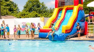 Campers sliding down the water slide into the pool